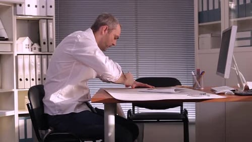Man Working on Architectural Blueprints in Office