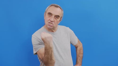 Angry Man Making a Fist Against Blue Background