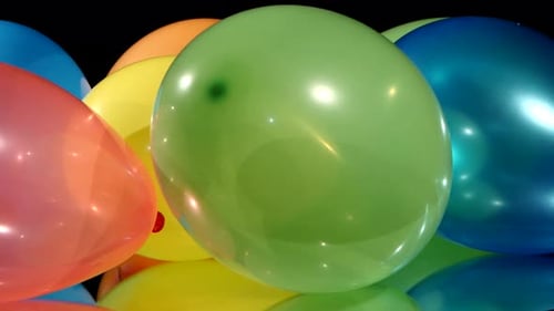 Mehrfarbige verschiedene Luftballons, Rotation, auf schwarzem Hintergrund