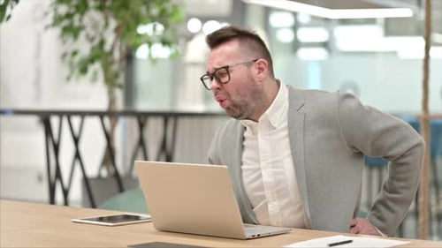 Man Experiences Back Pain While Working on Laptop