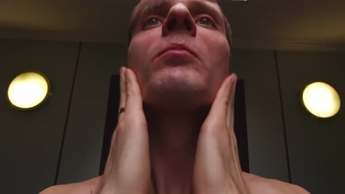 Man Applying Lotion to Face in Bathroom