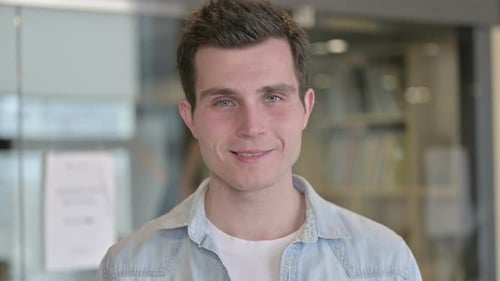 Porträt eines fröhlichen jungen Designers, der in die Kamera läch