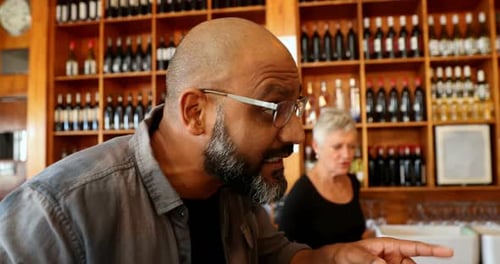 Friends toasting glass of beer at counter in bar 4k
