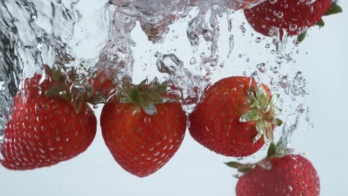 Ripe Red Strawberries Splashing into Water