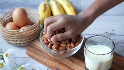 Hand Reaching into Bowl of Almonds for Healthy Snack
