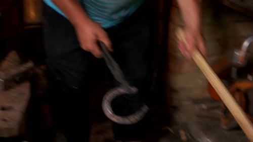 Blacksmith Shaping a Horseshoe by Hand in Workshop