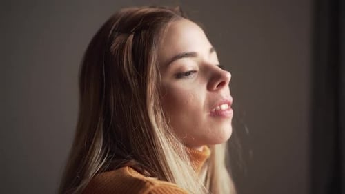 Woman Looks Out Window and Smiles