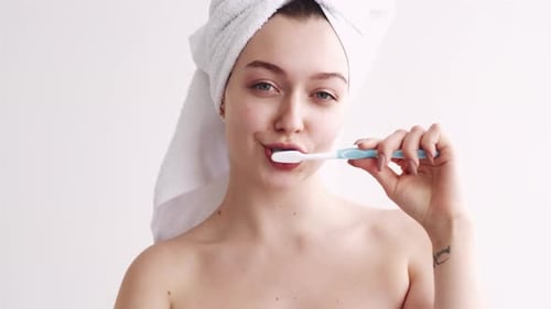 Young Woman Brushing Teeth in Bright Light