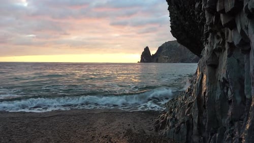 Colorful Warm Sunset Over the Sea and Volcanic Basalt Rocks Like in Iceland