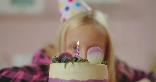 Close Up of Little Girl Blowing Out Candle on Birthday Cake in Slow Motion. Schoolgirl Celebrates