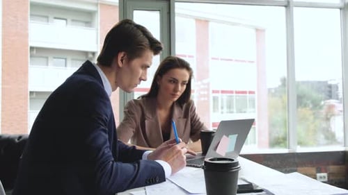 Man and woman work in comfortable modern office sitting at the table. Working process
