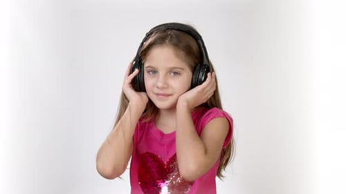Happy Emotions of a Little Girl in a Bright Pink Dress. A Little Girl with Headphones Dancing and