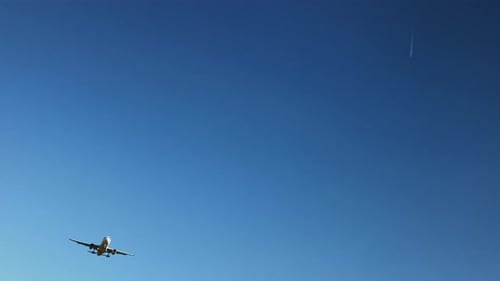 Airplane with Passengers on Blue Sky Background Landing on Landing Strip at Airport