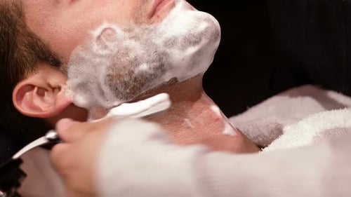 Homem tendo a barba raspada com navalha