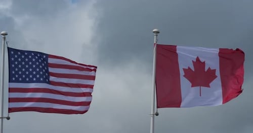 American and Canadian Flags Waving in the Wind
