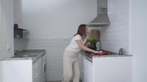 Woman Prepares Vegetables in Modern Kitchen Using Tablet