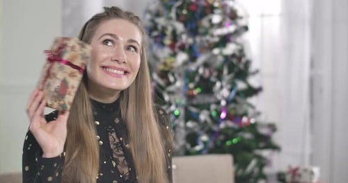 Woman Holds Christmas Present in Decorated Home