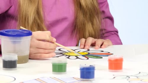 Girl Paints a Children's Figure with Paints and a Brush. Close Up