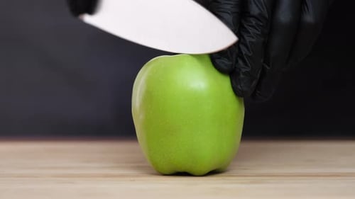 Schneidet einen Apfel mit einem Messer auf schwarzem Hintergrund in zwei Hälften