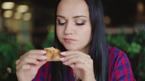 Brunette Woman Eating Pizza in Restaurant