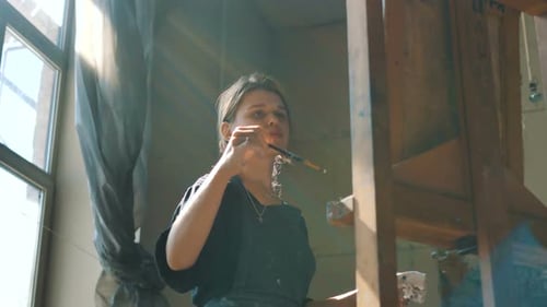 Woman Draws Picture Taking Paint From Palette in Art Studio