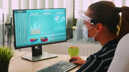 Woman Working at Computer with Face Shield and Mask