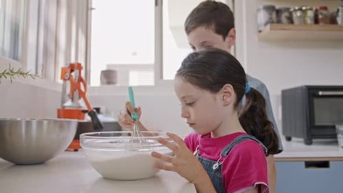 Kids preparing and mixing ingredients for pancakes in the kitchen