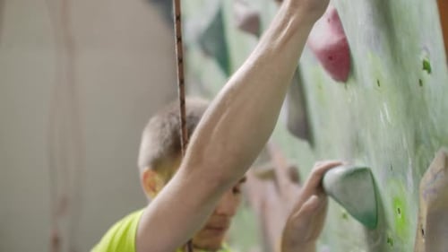Young Man Rock Climber is Climbing At Inside Climbing Gym