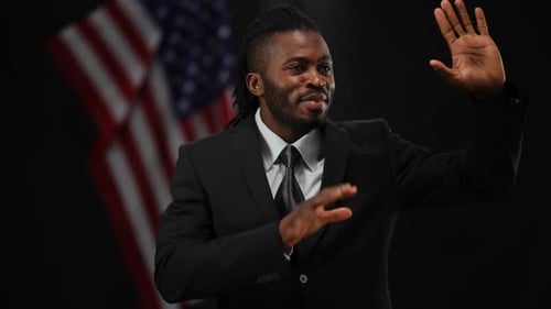 Portrait of Smiling African American Male Politician Greeting Public in Camera Flashes with USA Flag
