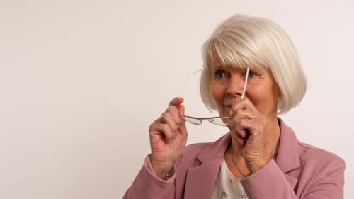 Senior Woman Puts On Different Pairs of Glasses