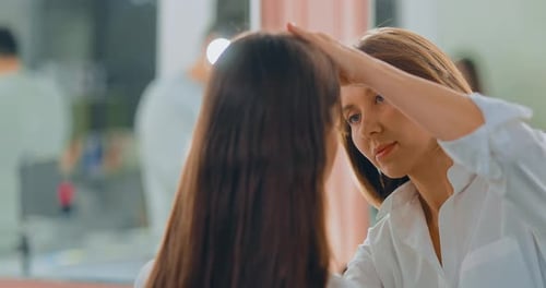 Woman Makeup Artist Working with a Model at a Large Mirror