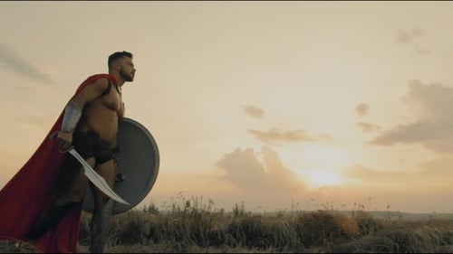 Shirtless Spartan Walking in Dry Field.