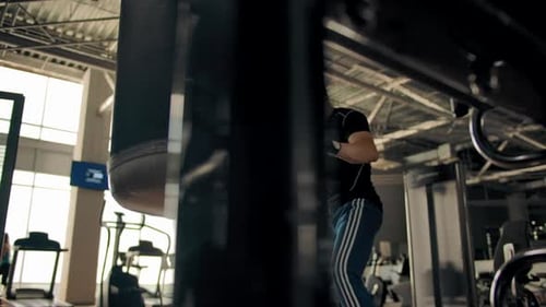 Man Hits and Kicks Punching Bag in Gym