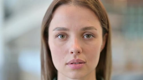 Nahaufnahme des Gesichts einer seriösen jungen Frau, die in die Kamera schaut
