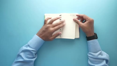 Top View of Man's Hand Turning a Pager of a Diary