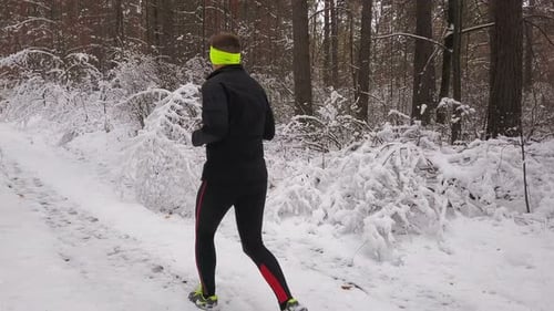 Athletic Man Runs Through Snowy Forest Landscape