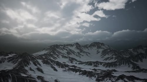 Dramatic Flyover of Snow-Capped Mountains Under Cloudy Sky