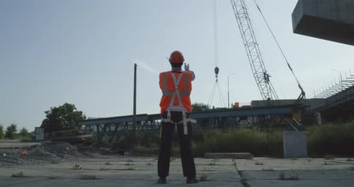 Construction Worker Overseeing Crane Operation on Job Site