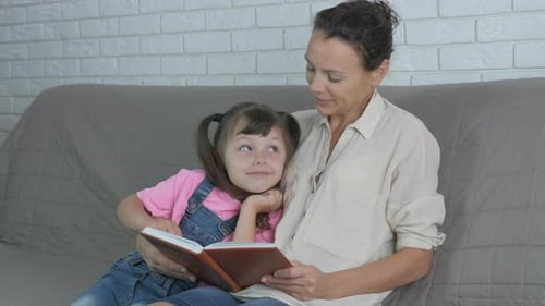 Mother Reads Story to Child on Couch