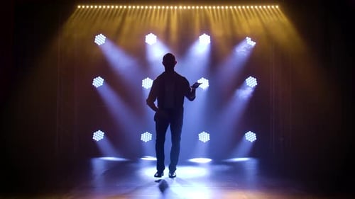 Hombre bailando música latina, bachata, merengue, salsa, filmado en un estudio oscuro con luces de neón en el