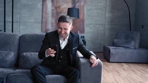 Handsome Man European Appearance in Classic Clothes in a White Shirt Sits in Stylish Dark Office on