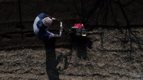 Aerial Drone View Man Farmer Working in the Garden Plows with Garden Tiller