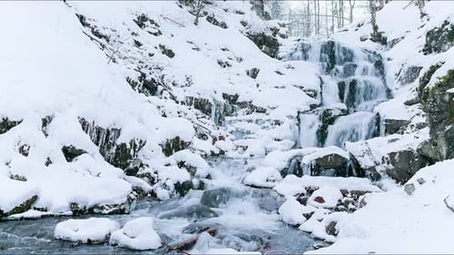 Wonderful frozen foot of a waterfall with a powerful stream of water at winter carpathian mountains