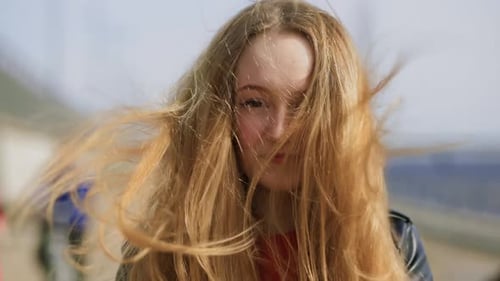 Une femme blonde touche les cheveux par temps venteux