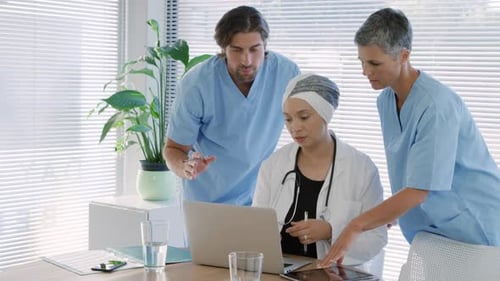 Medical Professionals Collaborate Using Laptop and Tablet
