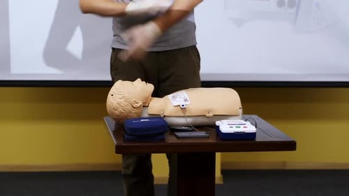 Demonstrator performs CPR On Medical Mannequin In Training