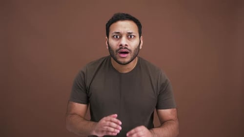 Nervous Indian Man Looking at Camera Seeing Something Terrible Feeling Panic Brown Studio Background