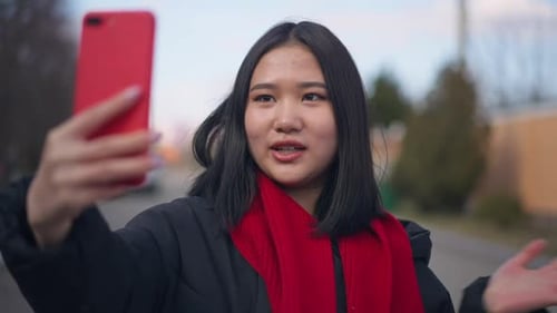 Young Beautiful Woman Using Video Call on Smartphone Standing Outdoors on Suburban Street
