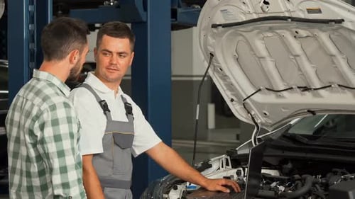 Car Mechanic and His Client Shaking Hands at the Automobile Service Station
