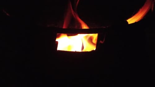 Bûches de bois brûlées au ralenti dans un tonneau la nuit
